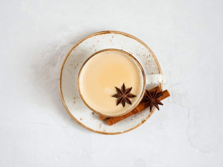 Chai tea in a cup on a saucer with star anise and cinnamon sticks.
