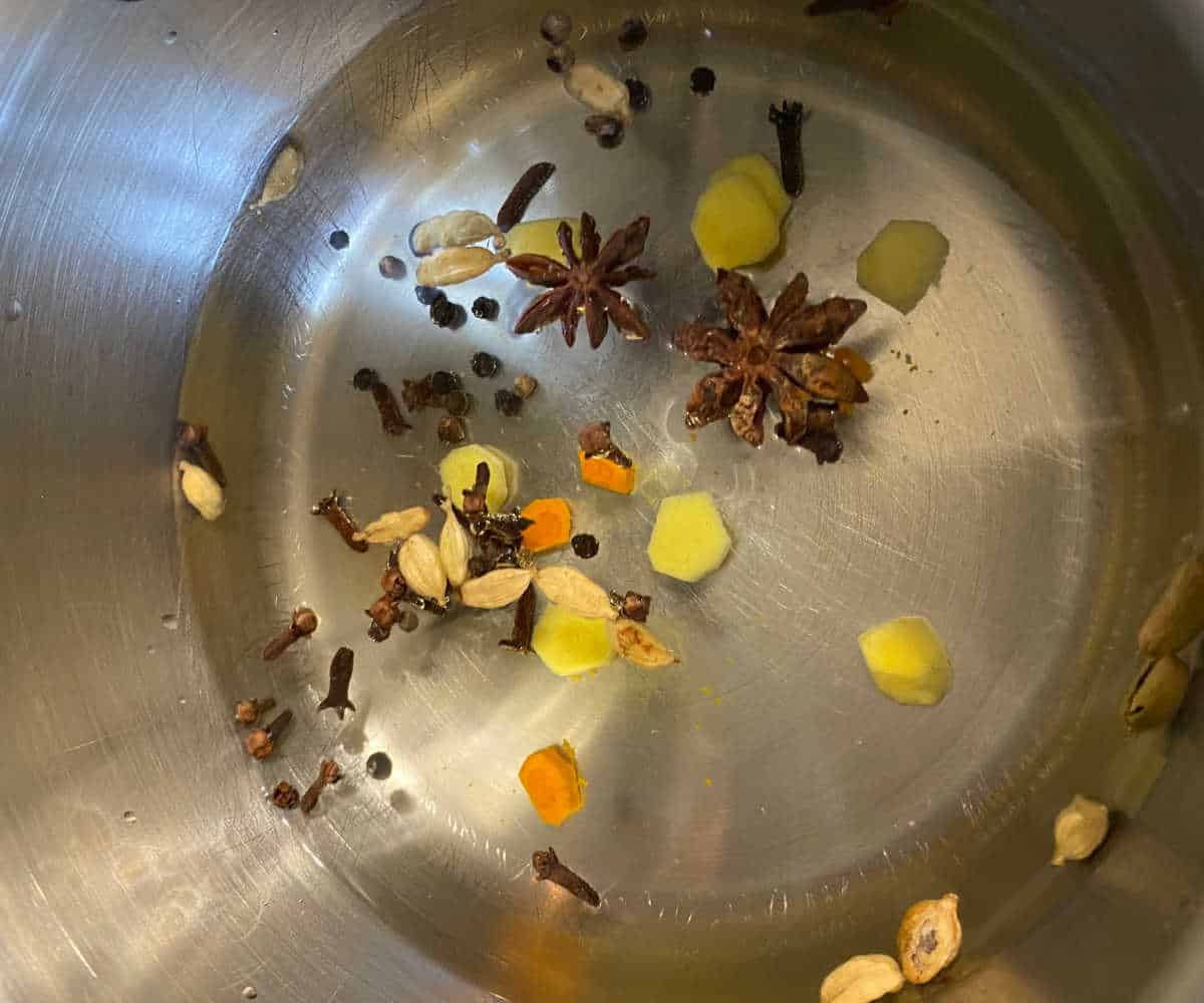Golden chai spices and water in a pot.