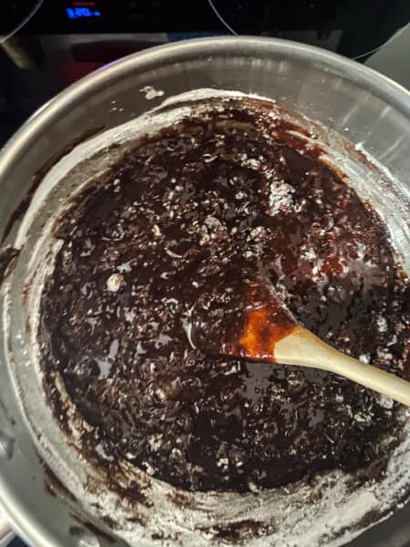 Brownie batter being stirred in a bowl with a wooden spoon.