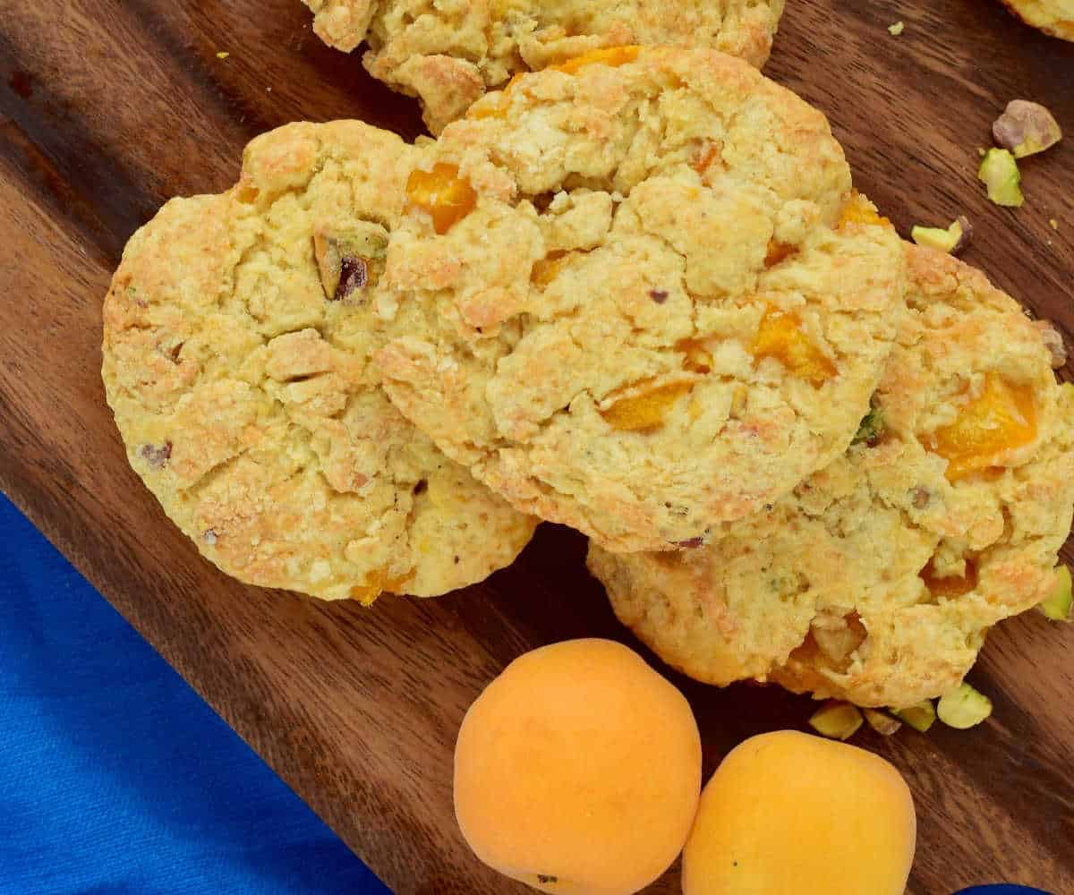 Apricot scones on cutting boards and a blue cloth with fresh apricots.