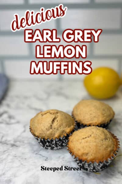 Three muffins in black and white muffin liners on a marble table with lemons and lemon zest. The text reads delicious Earl Grey lemon muffins.