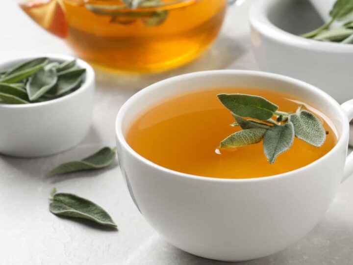Sage tea in a white cup with sage leaves.