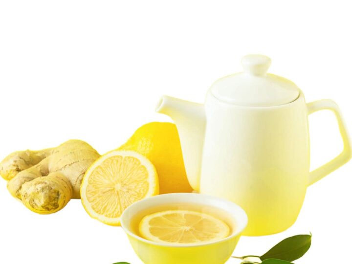 A white teapot and cup with ginger lemon tea and a lemon and a piece of ginger on a white background.