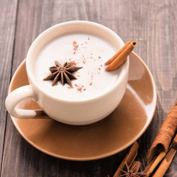 White chocolate chai in a stoneware cup and saucer with cinnamon sticks and star anise.