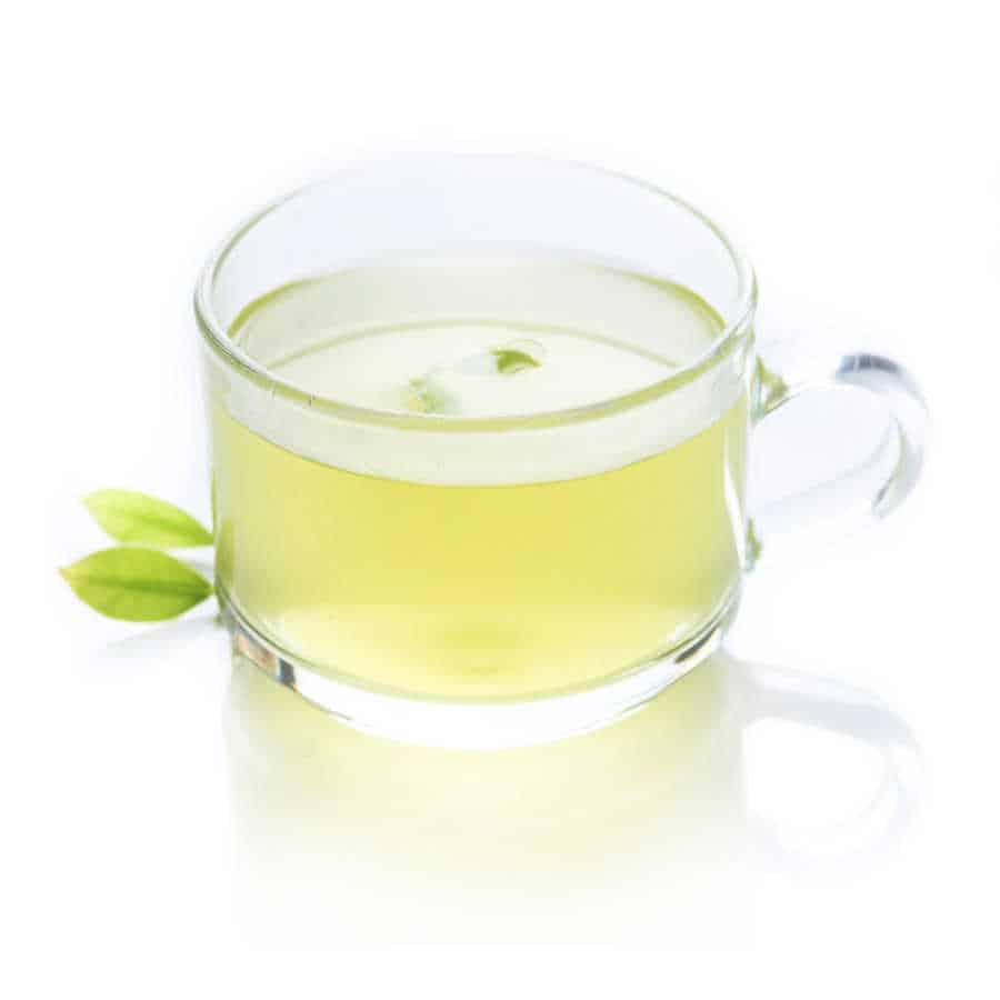 Green tea in a glass cup with a green leaf on a white background.
