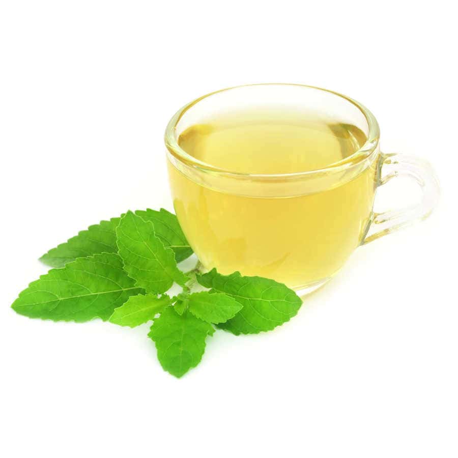 Tulsi tea in a glass cup with a tulsi leaf.