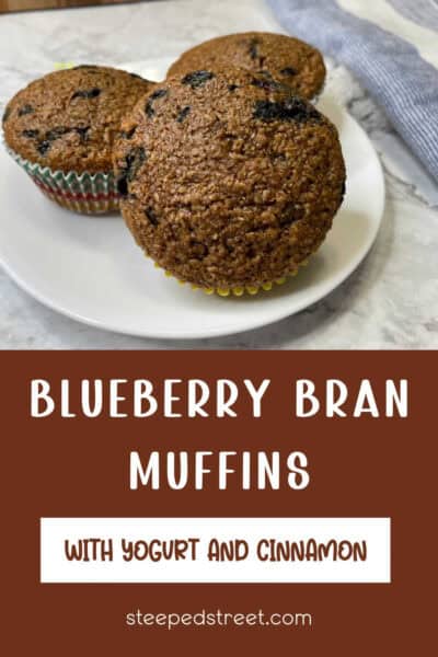 Three blueberry bran muffins on a white plate. The text reads Blueberry bran muffins with yogurt and cinnamon.
