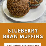 Three blueberry bran muffins on a white plate. The text reads Blueberry bran muffins with yogurt and cinnamon.