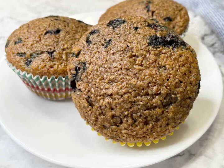 Three blueberry bran muffins on a white plate.