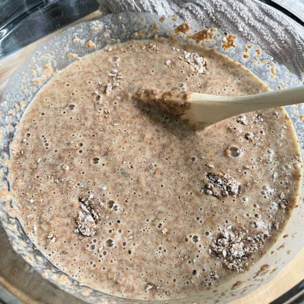 Muffin batter in a glass bowl with a wooden spoon.