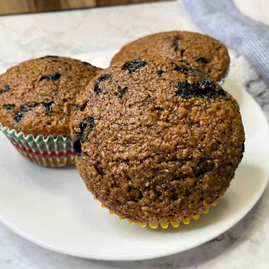 Three blueberry bran muffins on a white plate.