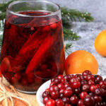 Fresh cranberry drink with oranges and cinnamon for holiday warmth.