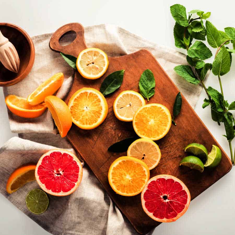 Simmer pot ingredients with citrus and herbs on a wooden board. The text reads How to make a simmer pot. Make your home smell amazing.