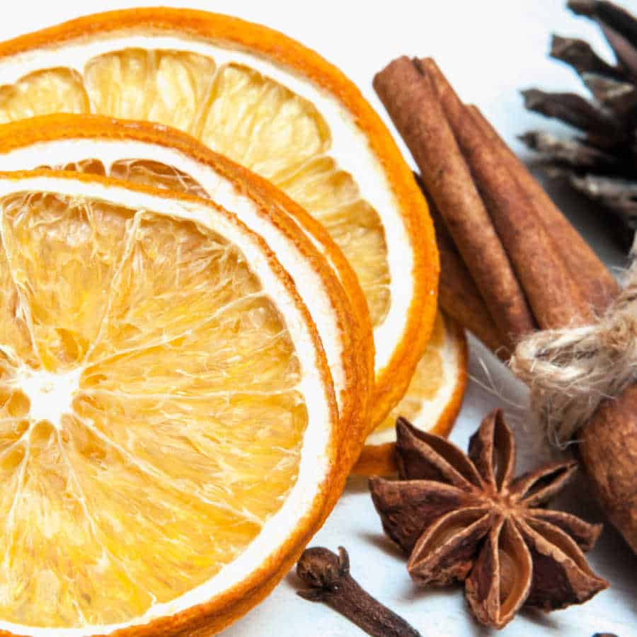 Orange slices, cinnamon sticks, cloves, and star anise on a white background.