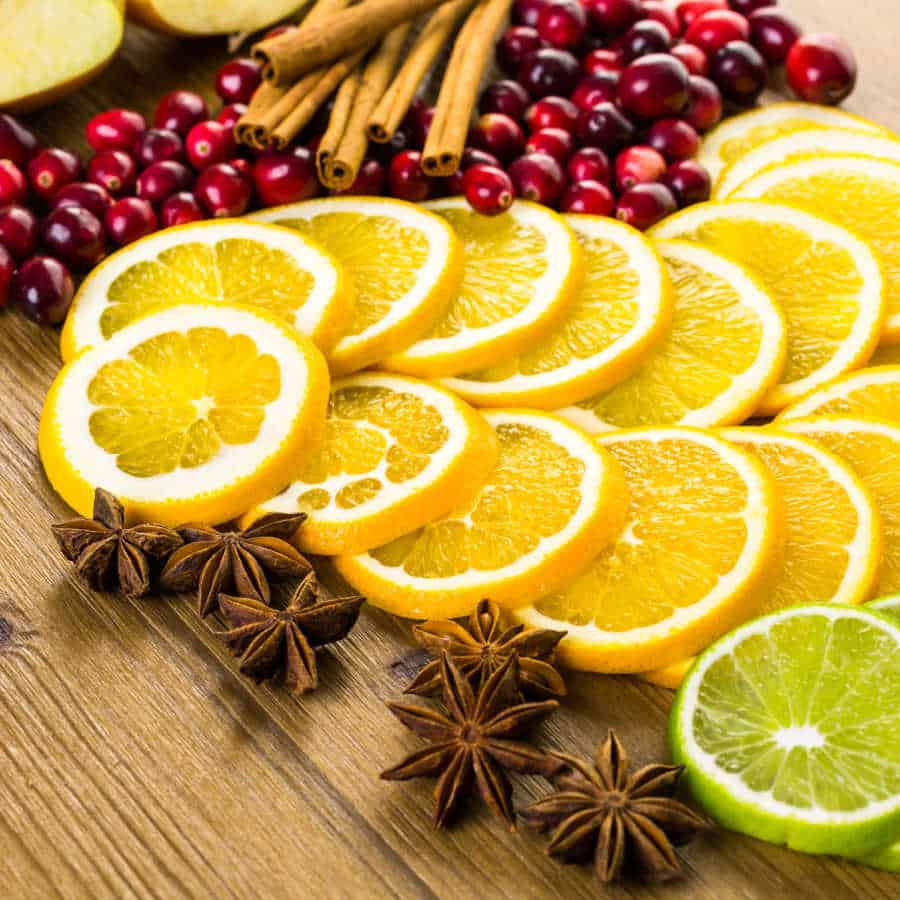 Citrus slices, cranberries, cinnamon sticks, and star anise on a wooden table.