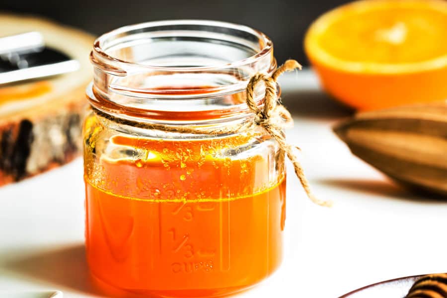 A small glass jar with orange spice simple syrup.
