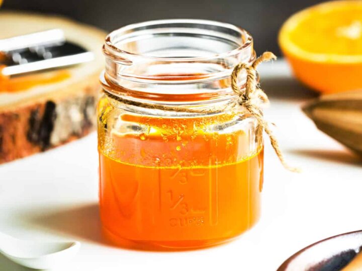 A small glass jar with orange spice simple syrup.