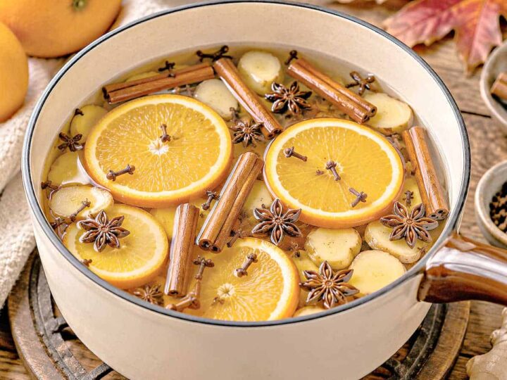 Cinnamon sticks, cloves, star anise and orange slices in a pot on a wooden table.