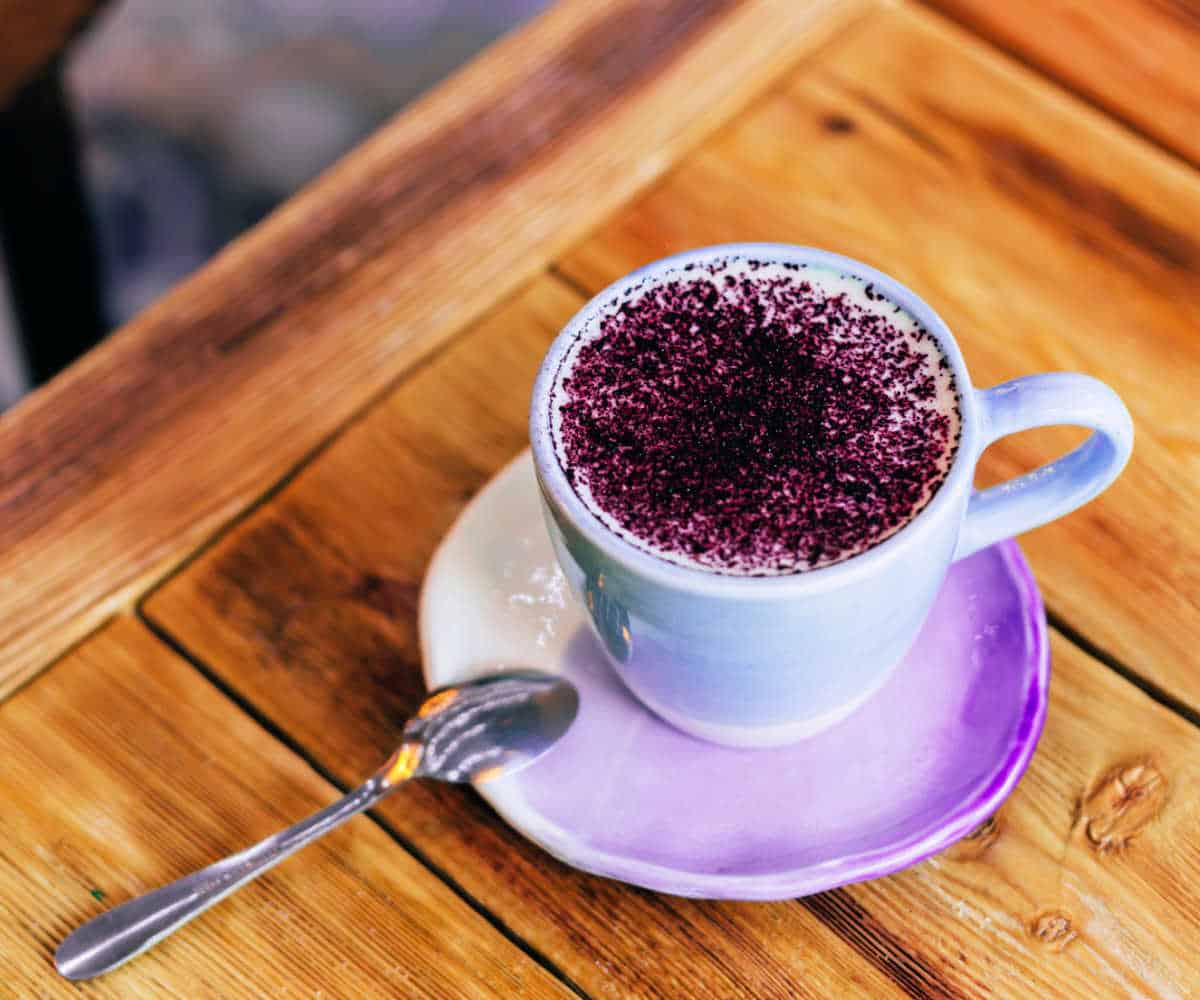 Earl Grey lavender latte in a purple cup and saucer on a wooden table.
