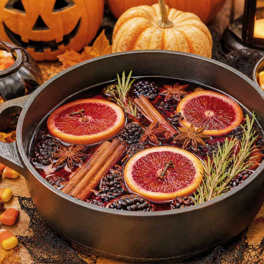 Halloween simmer pot in a cast iron pot surrounded with pumpkins.