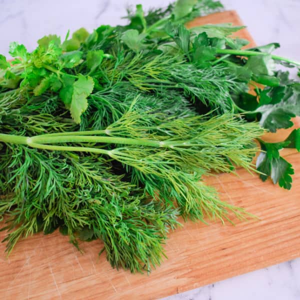 Fresh herbs on a wooden cutting board.
