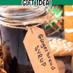 Gingerbread syrup in a jar with a brown label surrounded by Christmas bulbs and cookies. The text reads homemade gingerbread syrup gift idea.