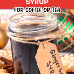Gingerbread syrup in a jar with a brown label surrounded by Christmas bulbs and cookies. The text reads homemade gingerbread syrup for coffee or tea.